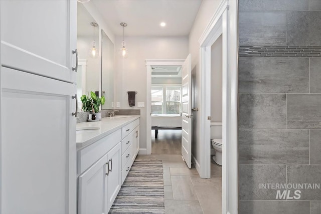 ensuite bathroom with double vanity, toilet, ensuite bath, a sink, and recessed lighting