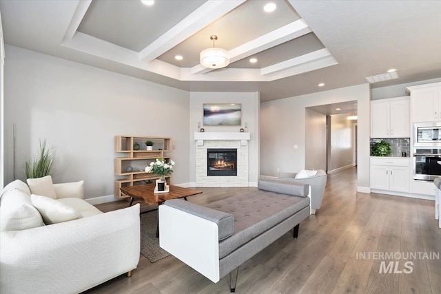 living room with recessed lighting, a stone fireplace, light wood-style flooring, and baseboards