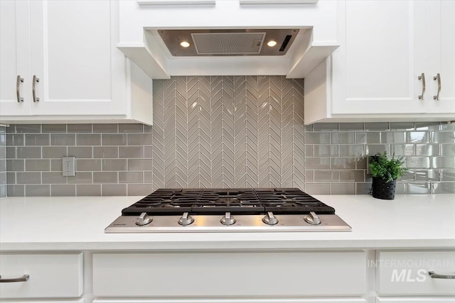 kitchen with stainless steel gas cooktop, light countertops, exhaust hood, and white cabinetry