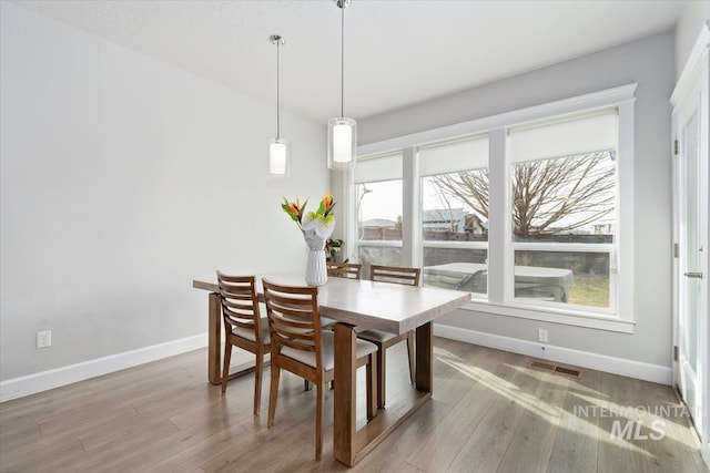 dining space featuring baseboards, visible vents, and wood finished floors