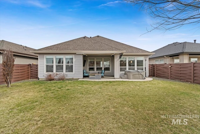 back of property with a fenced backyard, roof with shingles, a patio, and a yard