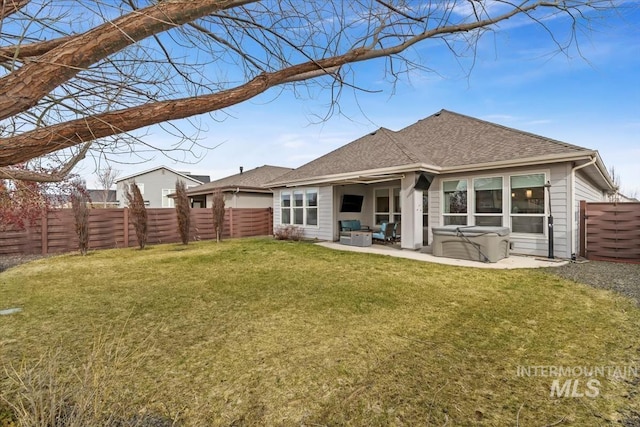 rear view of house with a fenced backyard, roof with shingles, a lawn, a patio area, and a hot tub