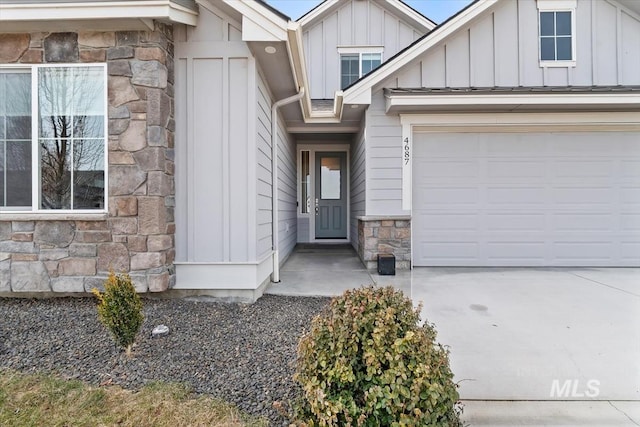 property entrance with a garage, stone siding, board and batten siding, and concrete driveway