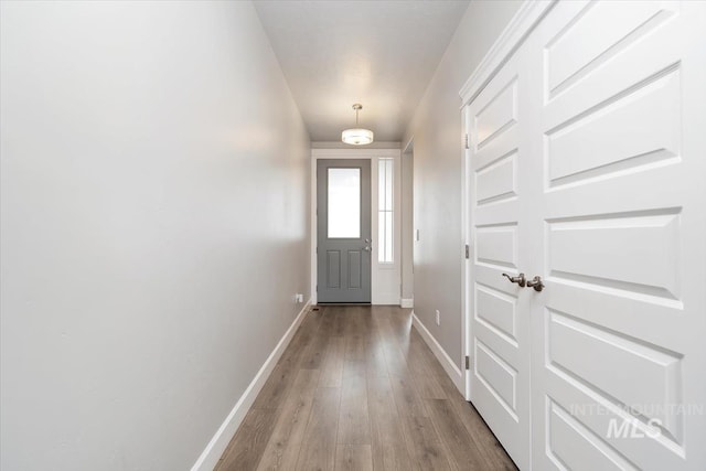 doorway featuring baseboards and wood finished floors