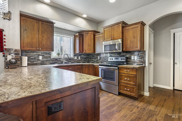 kitchen featuring dark wood-style floors, a sink, stainless steel appliances, and tasteful backsplash
