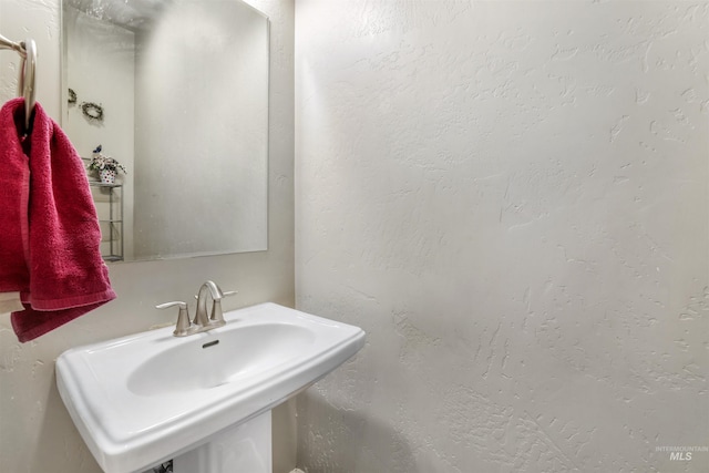 bathroom featuring a textured wall and a sink