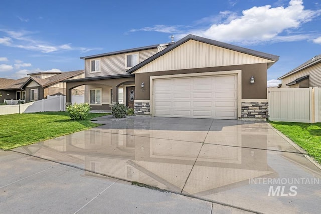 view of front facade featuring stone siding, fence, a garage, a front yard, and driveway