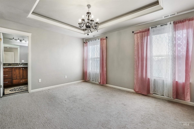 unfurnished bedroom featuring carpet flooring, a tray ceiling, visible vents, and a notable chandelier