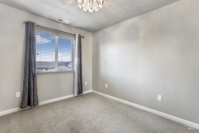 spare room with baseboards, a notable chandelier, visible vents, and carpet floors