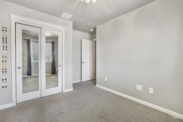 unfurnished bedroom featuring baseboards, visible vents, a notable chandelier, and carpet