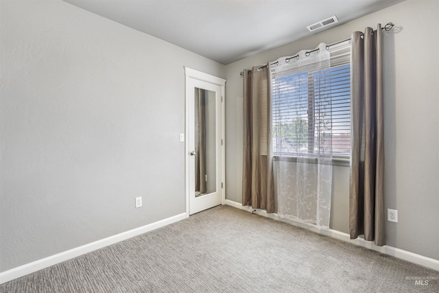 spare room with baseboards, visible vents, and carpet