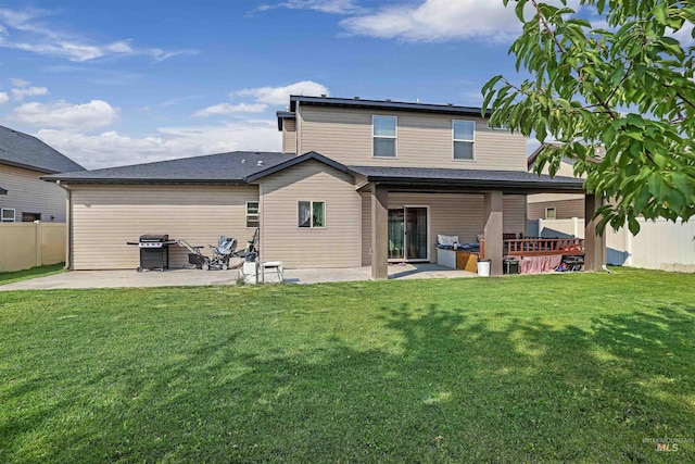 rear view of property featuring a patio, fence, and a lawn