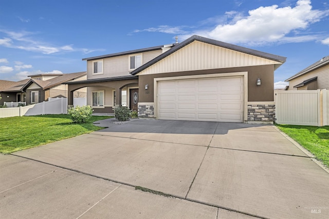 view of front of home featuring driveway, a front yard, stone siding, fence, and a garage