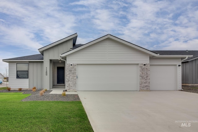 view of front of home featuring a garage, concrete driveway, stone siding, board and batten siding, and a front yard