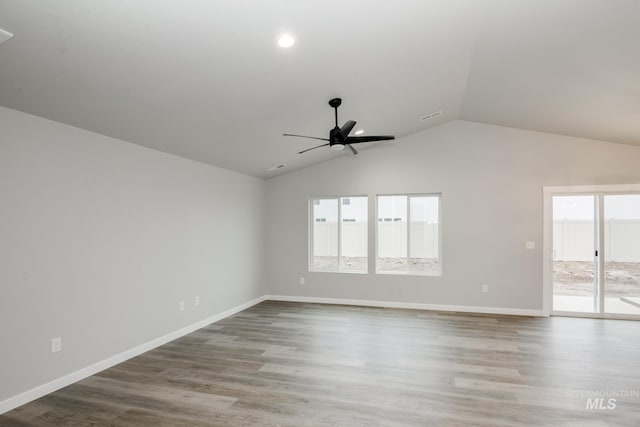 spare room with ceiling fan, vaulted ceiling, baseboards, and wood finished floors