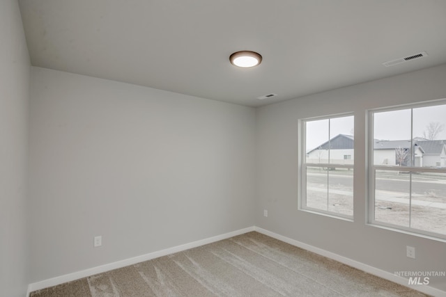 empty room with light colored carpet, visible vents, and baseboards