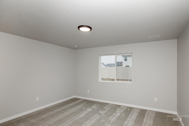 empty room with carpet floors, visible vents, and baseboards