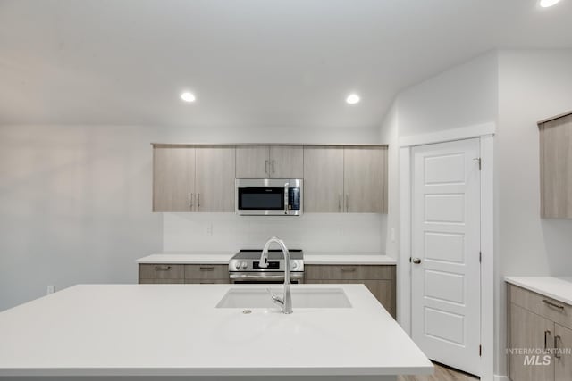 kitchen featuring stainless steel appliances, light countertops, backsplash, an island with sink, and modern cabinets