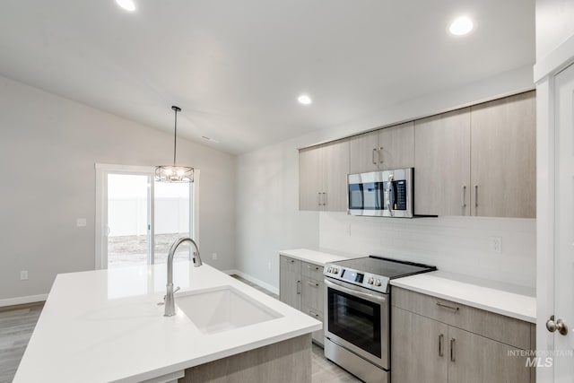 kitchen with lofted ceiling, appliances with stainless steel finishes, a sink, light countertops, and backsplash