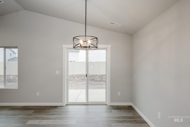 unfurnished dining area featuring lofted ceiling, visible vents, baseboards, and wood finished floors