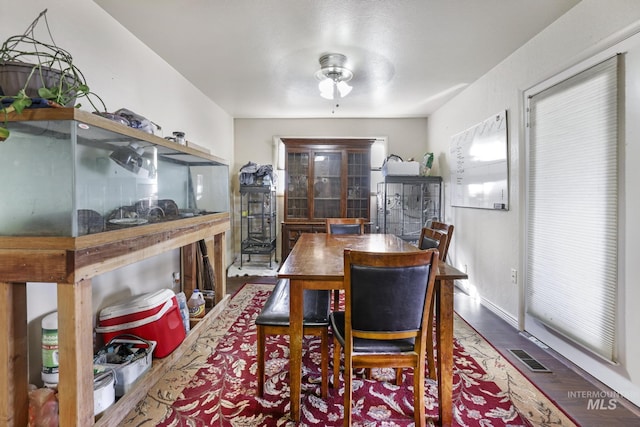 dining space featuring a ceiling fan, wood finished floors, visible vents, and baseboards