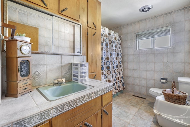 full bathroom with toilet, backsplash, a shower with shower curtain, tile walls, and vanity