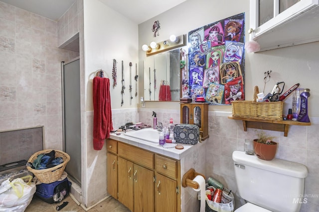 bathroom with toilet, tile walls, wainscoting, a shower stall, and vanity