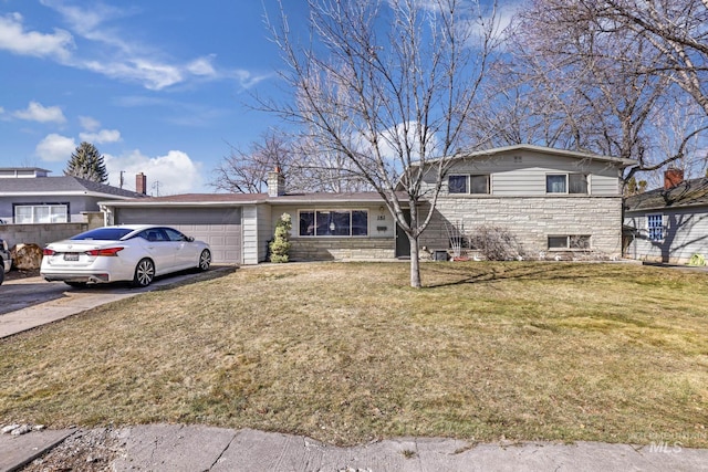 split level home featuring a front yard, a chimney, a garage, stone siding, and driveway