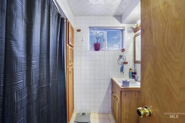 bathroom with tile patterned flooring, curtained shower, tile walls, and vanity