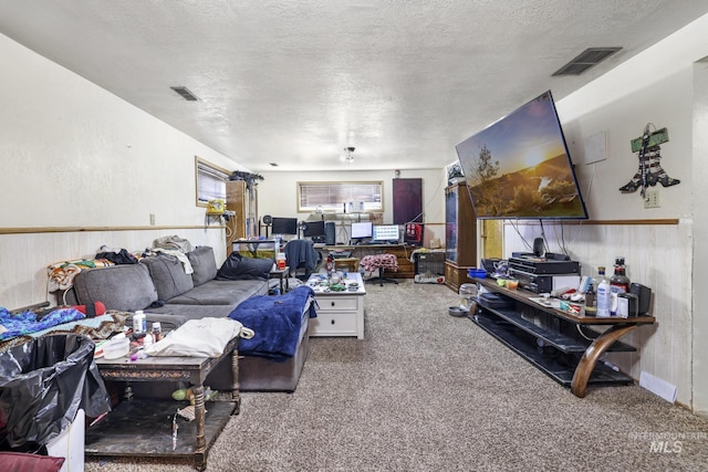 living area featuring visible vents, a textured ceiling, a wainscoted wall, and carpet flooring