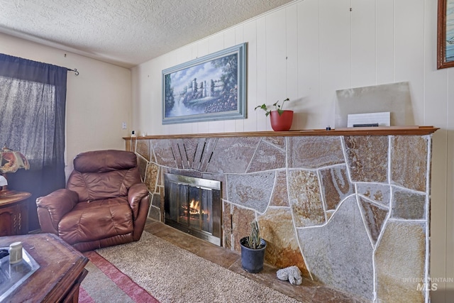 living area with a stone fireplace and a textured ceiling