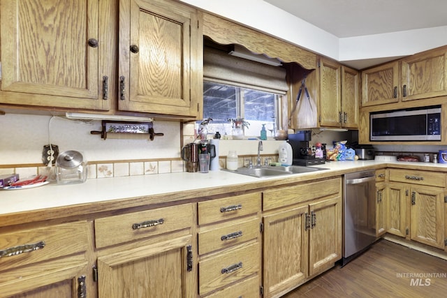 kitchen with appliances with stainless steel finishes, light countertops, and a sink