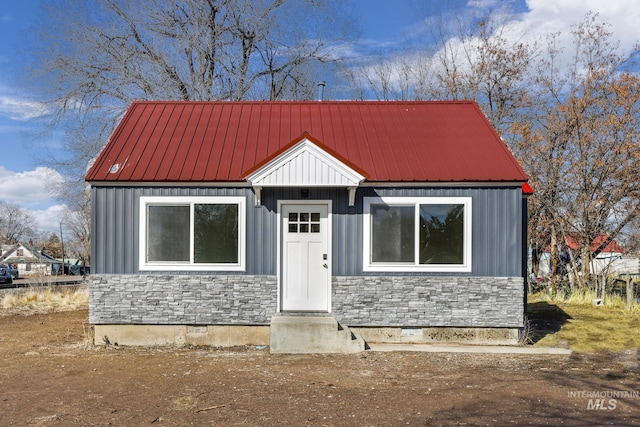 view of front facade featuring entry steps, stone siding, metal roof, and crawl space