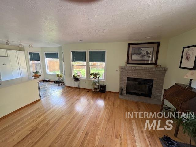 3707 N Jullion Way, Boise, ID 83704 - living area featuring a textured ceiling, wood finished floors, a fireplace, and baseboards