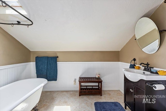 204 7th Ave N, Twin Falls, ID 83301 - bathroom featuring a freestanding tub, vanity, vaulted ceiling, and a wainscoted wall