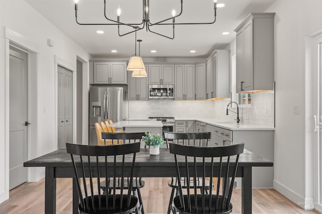 interior space featuring pendant lighting, gray cabinetry, sink, and stainless steel appliances