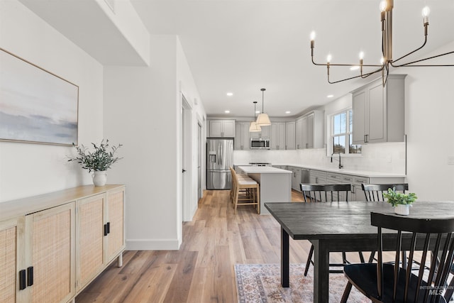 dining area with light hardwood / wood-style floors and a notable chandelier