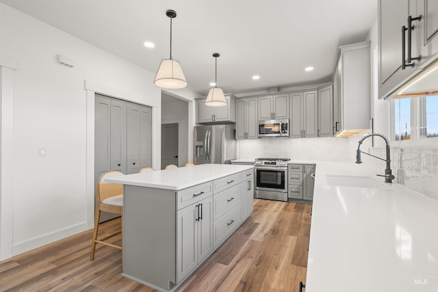 kitchen featuring a center island, stainless steel appliances, gray cabinetry, and sink