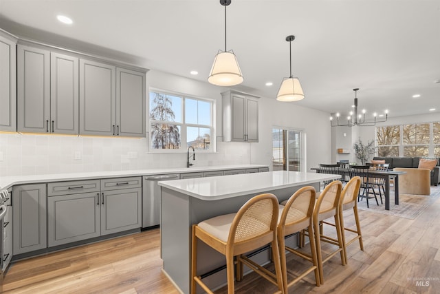 kitchen featuring gray cabinetry, dishwasher, hanging light fixtures, light hardwood / wood-style floors, and a kitchen island