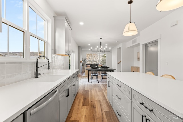 kitchen with dishwasher, sink, a healthy amount of sunlight, hanging light fixtures, and tasteful backsplash