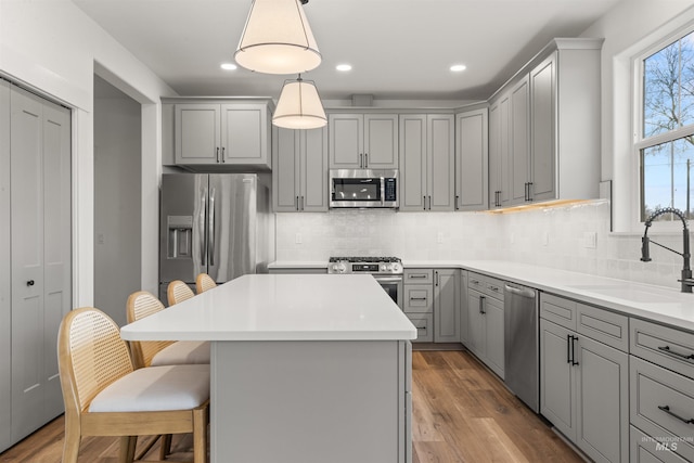 kitchen featuring decorative light fixtures, stainless steel appliances, gray cabinets, and sink