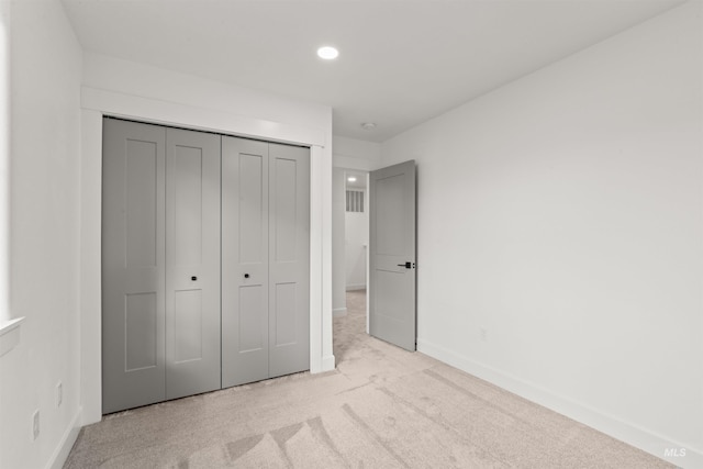 unfurnished bedroom with light carpet and a closet