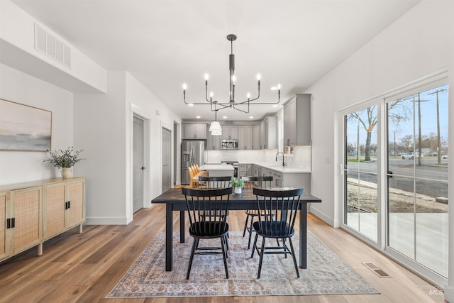 dining area with wood-type flooring, sink, and a chandelier