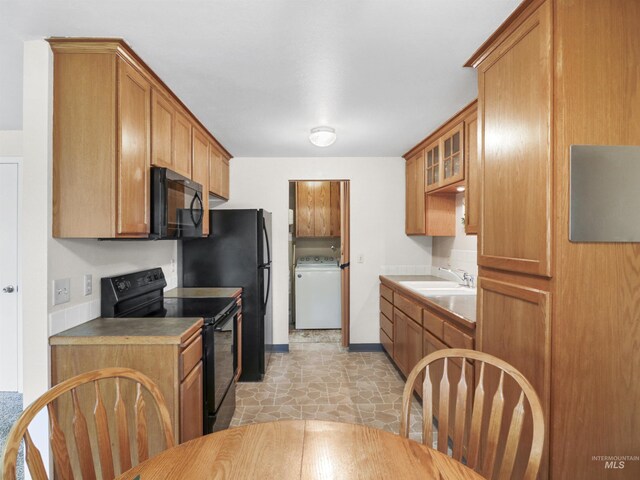 143 E Morris Ct, Kuna, ID 83634 - kitchen featuring black appliances, washer / dryer, glass insert cabinets, and brown cabinetry