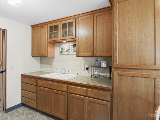 143 E Morris Ct, Kuna, ID 83634 - kitchen with glass insert cabinets, brown cabinetry, decorative backsplash, and light countertops