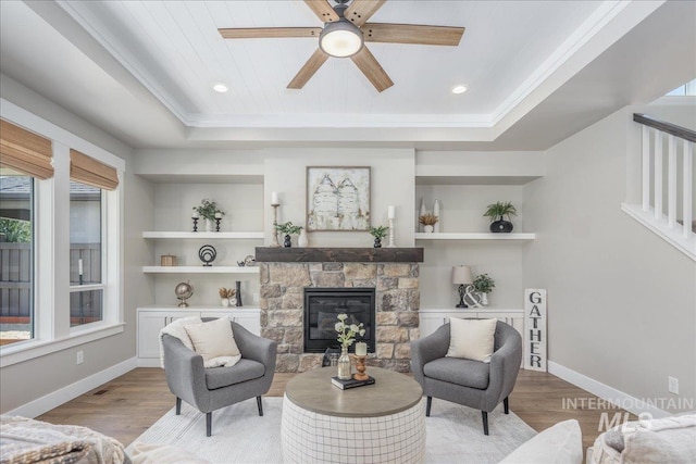 1864 N Highbury Way, Eagle, ID 83616 - living room with light wood finished floors, a tray ceiling, a stone fireplace, a ceiling fan, and crown molding
