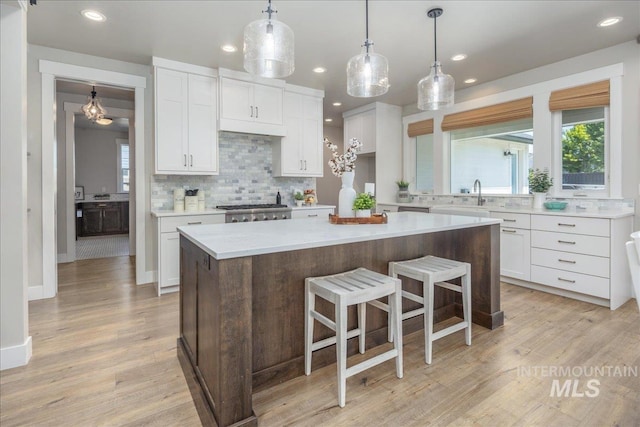 1864 N Highbury Way, Eagle, ID 83616 - kitchen featuring white cabinets, decorative backsplash, light countertops, a breakfast bar, and recessed lighting