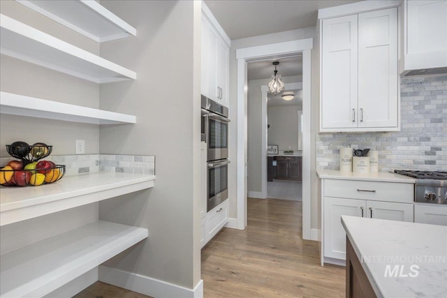 1864 N Highbury Way, Eagle, ID 83616 - kitchen with stainless steel appliances, decorative backsplash, light wood-style floors, and white cabinets