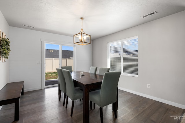 dining space with visible vents, a wealth of natural light, a notable chandelier, and dark wood finished floors
