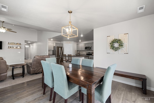dining space with visible vents, wood finished floors, baseboards, and ceiling fan with notable chandelier